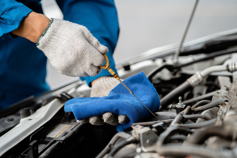 Close-up, a car mechanic checking the oil in a car's engine